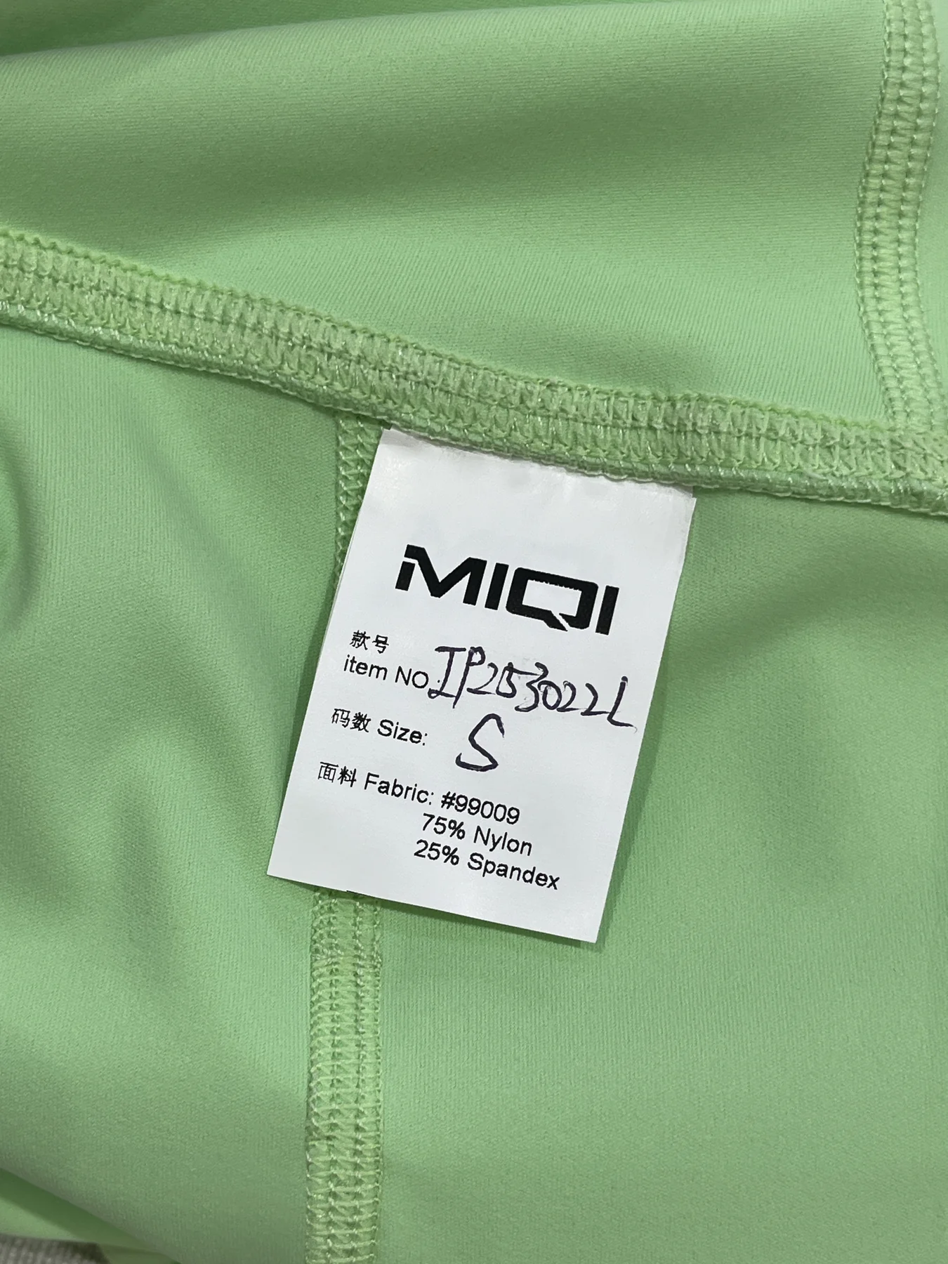 MIQI care and composition label applied to a green activewear garment