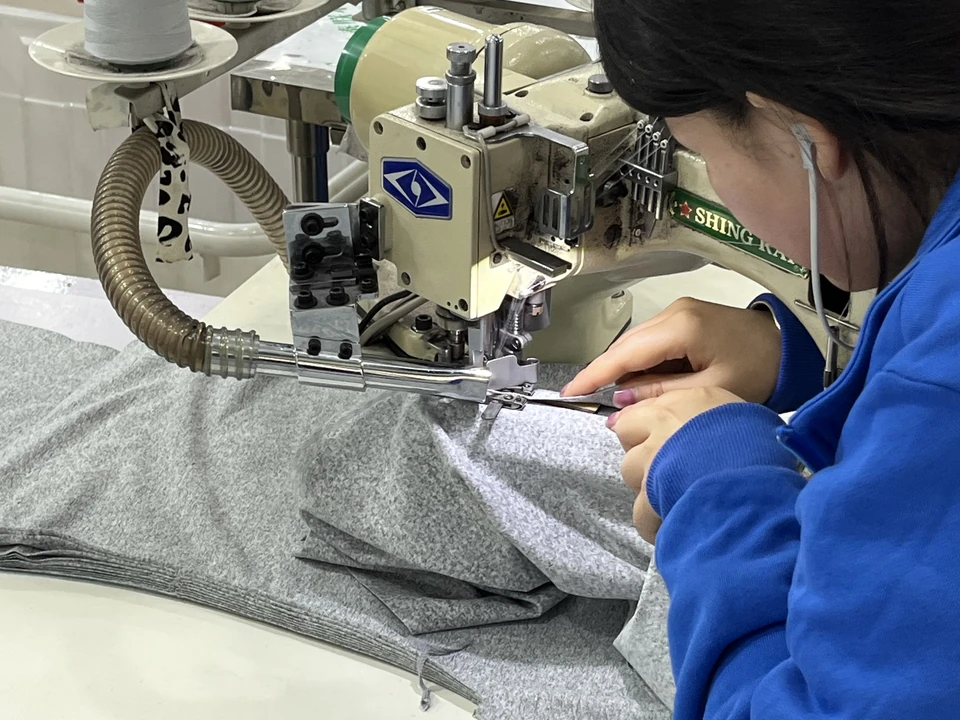 MIQI technician sewing an activewear sample on specialized equipment